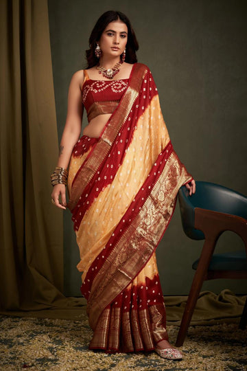 Woman wearing a traditional maroon and beige saree with jewelry against a neutral background
