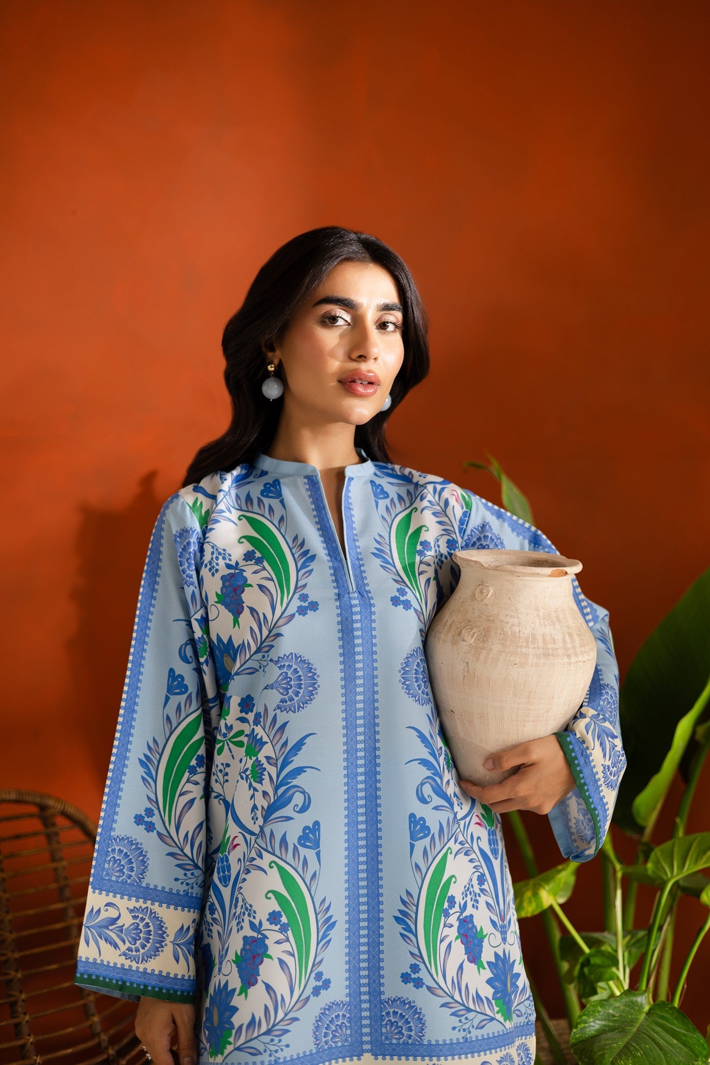 Woman holding a ceramic pot against an orange wall